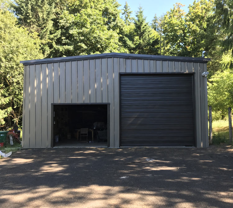 Commercial or industrial coating on a large metal barn/carport in the Kansas City area, showing a fresh coat of gray paint and a black overhead door