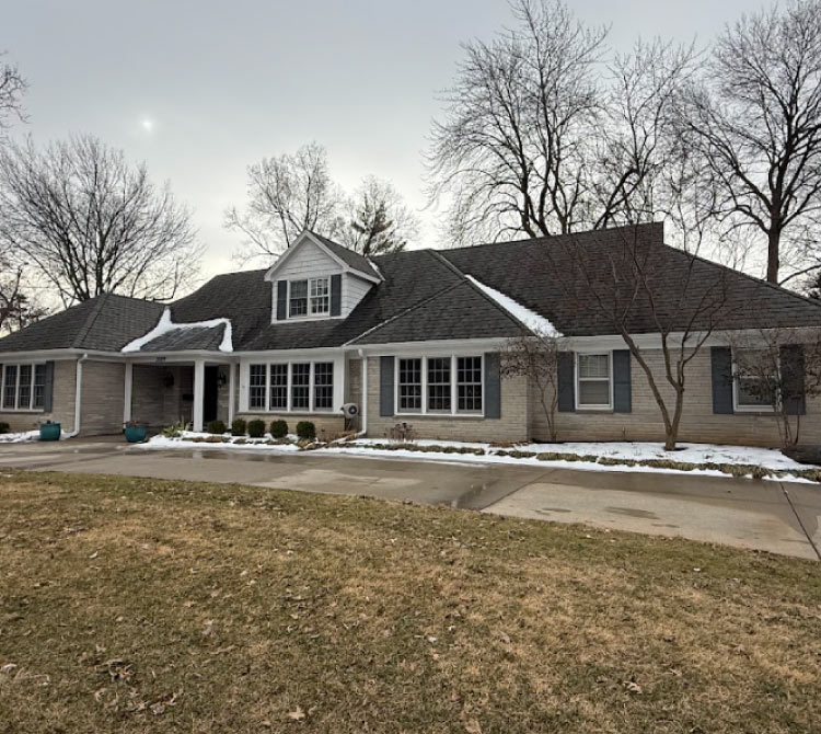 Residential exterior painting during winter in the Kansas City area, showing a brick ranch-style home with light gray trim and dark shutters