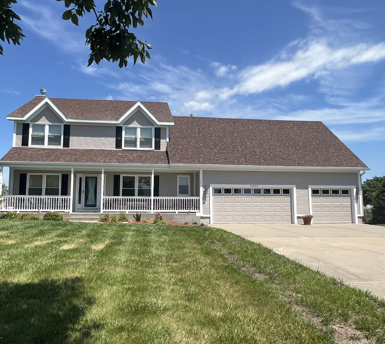 Completed residential exterior painting on a two-story suburban home in Kansas City, MO, featuring light gray siding and a brown roof