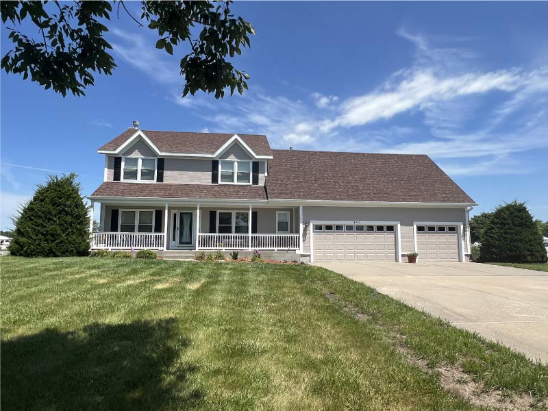 Large two-story residential home with freshly painted beige siding and white porch railing representing a whole house exterior project.