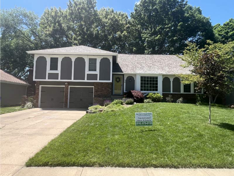 Modern grey exterior paint transformation on a ranch-style home with Elite 77 Painters branding and landscaping