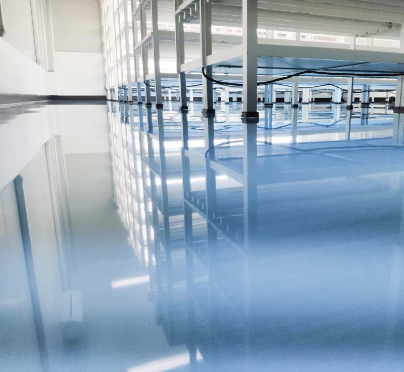 A highly reflective, light blue industrial coating on a warehouse floor, demonstrating the polished and professional look of a completed Elite77 project.