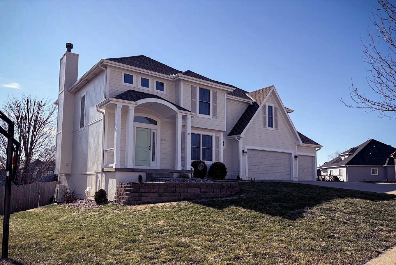 Two-story home freshly painted in light beige with mint green front door - Elite77 Painters Kansas City