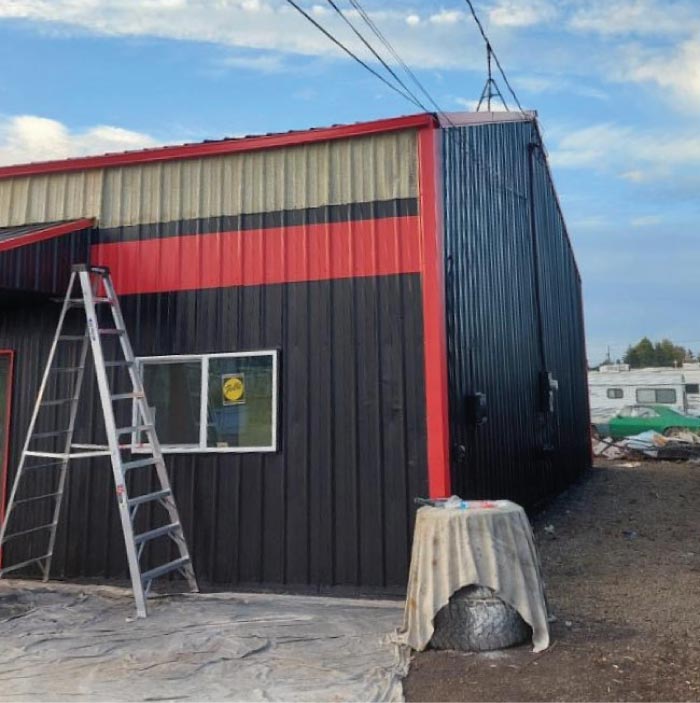 Metal warehouse exterior freshly painted black with red trim by Elite77 Painters in Kansas City