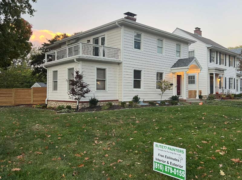 White two-story colonial home with new exterior paint, red front door and wrought iron balcony, painted by Elite77 Painters